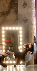 A stylish salon scene showcasing the interaction between stylist and client, with striking mirror reflections He looks after the lady, assisting in putting on shoes.