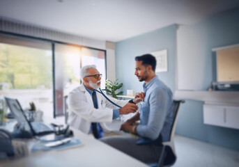 Obraz premium A doctor in a white coat listens to a patient's heart with a stethoscope.