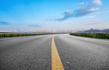 Scenic Winding Road Leading to City Skyline Under Blue Sky
