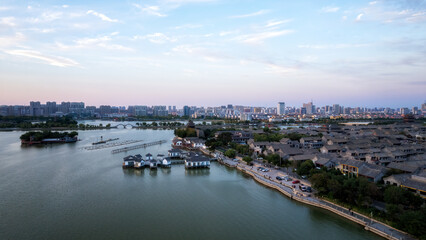 Naklejka premium Serene Waterfront Cityscape at Sunset with Tranquil Waters and Urban Skyline