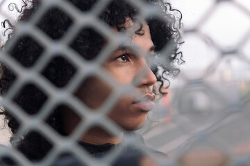 side view of thoughtful teen african american male with curly hair looking away while standing...