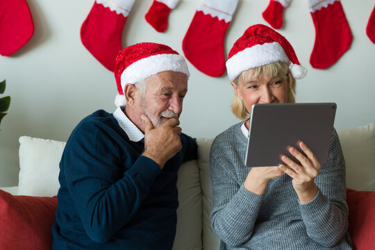 Senior couple using digital tablet on Christmas day. Elderly couple with digital tablet at home. Merry Christmas and Happy Holidays