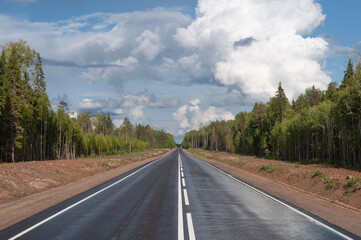 Fototapeta premium New empty asphalt road through the forest, summer time, clouds in blue sky