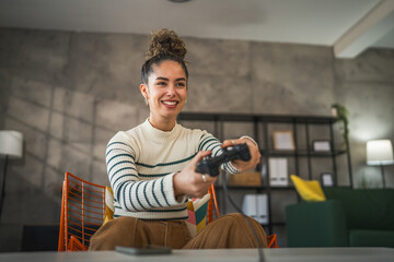 One young woman hold joystick play console video game at home © Miljan Živković