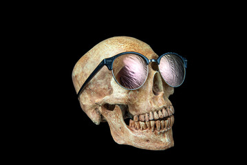 Human skull wears sunglasses on black background