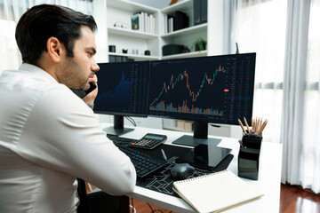 Trader businessman calling to consultant or partner with two stock exchange investment, compare...