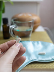 A woman cannot fall asleep and wants to drink a capsule with melatonin, a sleeping pill. Manifestations of jitlag or insomnia. Regulation of biological rhythms