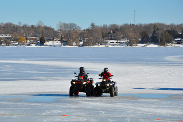 Two people riding an all terrain vehicle over frozen lake