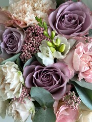 Bouquet of purple and beige roses, pink carnations, pink eustoma, white freesia and eucalyptus in...
