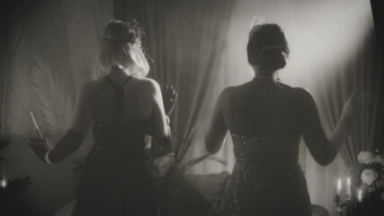 Old film 1920s style black and white color two women dancing at night club evening ball, dark room night club. Happy Girls have fun at Stylized party old retro style roaring twenties. Sexy girl dress