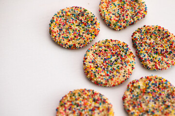 sprinkle covered sugar cookies on white background 