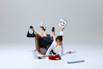Businesswoman in mid-task, balancing clipboard, phone, and coffee cup while reviewing papers on...
