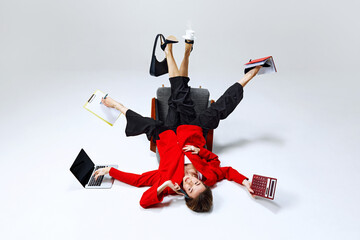 Businesswoman balancing her tasks with one foot in air, holding clipboard, calculator, and coffee....