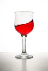 Single glass of red cabernet pino merlot malbec wine with bubbles and deep red glow isolated on white background