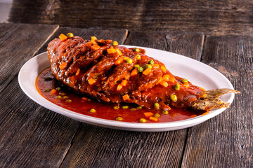 fried fish in sweet and sour sauce on wood table. Chinese food. food concept.