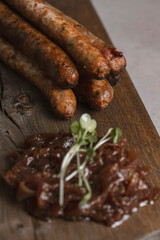 Grilled sausages with mustard and herbs on a wooden board