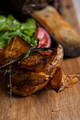 roasted veal rib with baked potatoes and vegetables on a wooden board