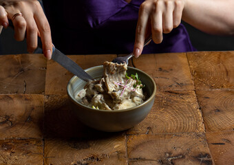 Woman eating rack of lamb in cream sauce with apple and radish in a bowl