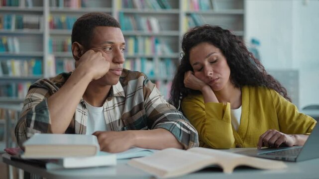 Tired African American man Latino Indian Arabian woman students classmates boredom sleepy textbooks books typing laptop teamwork difficult project exam university high school library page female male