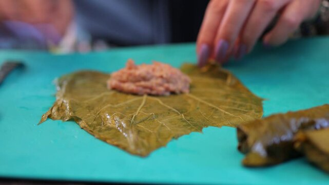 People cook dolma food.
Grape leaves stuffed with minced meat.