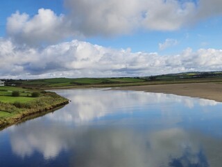 Serene Waterscape: Tranquil River With Gentle Waves And Cloud Reflections