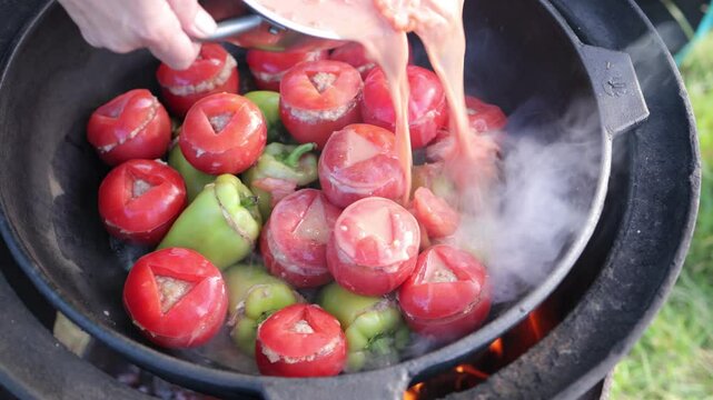 People hands are preparing food. Peppers, tomatoes, zucchini and grape leaves stuffed with minced meat.