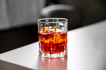 Close-up of a glass with amber liquid and ice cubes, set against a blurred background. The focus on the drink highlights its refreshing appeal, making it ideal for stock photography