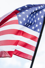 Obraz premium The American flag flutters vibrantly in the breeze, showcasing its stars and stripes under a bright sky.