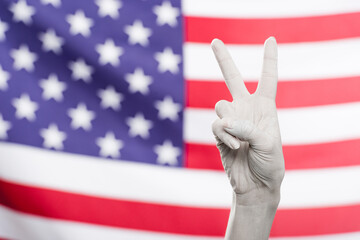 A white hand gestures peace, symbolizing honor and patriotism against the backdrop of the American...