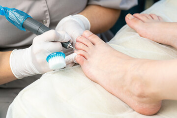 Professional hardware pedicurist, podiatrist cleaning nails using a nail miller