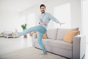 Photo of handsome bearded alone mature age man staying home dance boogie woogie style with headphones in his new house indoors