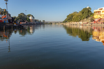 Obraz premium pristine holy Shipra river shore with ancient temple and bright blue sky at morning