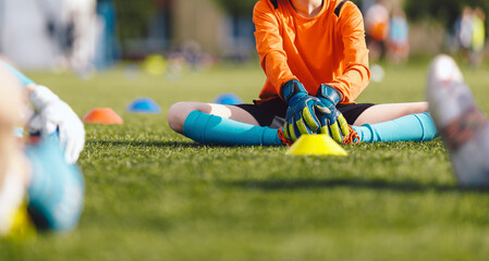 Kids in Football Goalkeepers Training. Young Boy Doing Soccer Stretching Exercises. Group of School Boys in Soccer Goalie Practice During Summer Time. Youth players in Soccer Gloves and Cleats © matimix