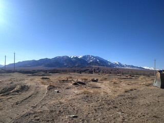 Serene landscape featuring majestic snow-capped mountains under a clear blue sky in a remote desert area during daylight hours