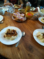 Gathered around a rustic wooden table, family shares a hearty meal featuring mashed potatoes, savory dishes, and colorful salads in a warm atmosphere
