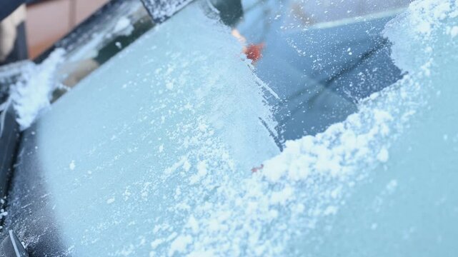 Woman deicing car windshield with ice scraper, 4K 120 fps slow motion
