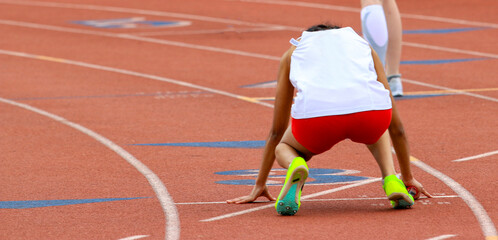 Fototapeta premium Female runner ready to start a sprint relay race on an outdoor track