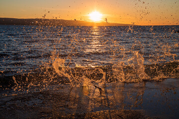 Sea waves splashing against the promenade in Brela, Croatia at sunset