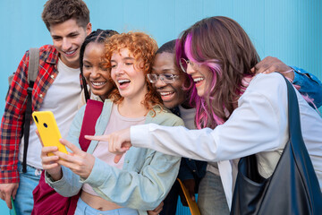 Group of friends pointing looking at their smartphones Multiracial teenagers surfing the internet with mobile phone on campus