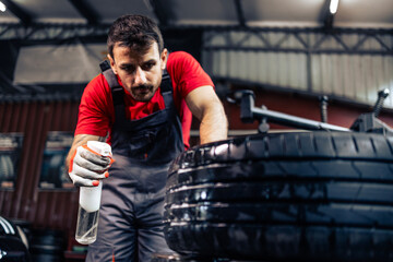 Professional tire repairman searching for a place of puncture on the car wheel.