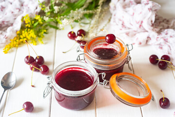 Cherry jam in a glass jar on a white background. Sweet dessert. Close-up.