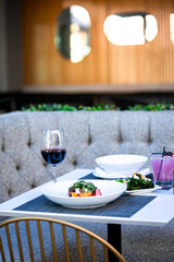 Gourmet beet salad with roasted beets, greens, nuts, cheese, elegantly plated in a modern dining setting. A pink cocktail and another dish blur in the background, enhancing the fine dining ambiance
