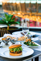 A visually appealing table setting with a variety of dishes, including seafood, salad, and a burger, perfect for a luxurious outdoor dining experience.