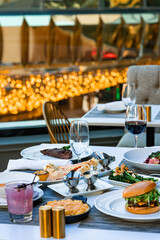 A visually appealing table setting with a variety of dishes, including seafood, salad, and a burger, perfect for a luxurious outdoor dining experience.