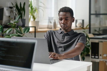 African American programmer writing codes in modern office of famous IT company
