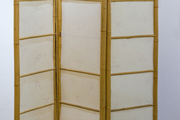 Fragment of folding bamboo screen against the wall indoor