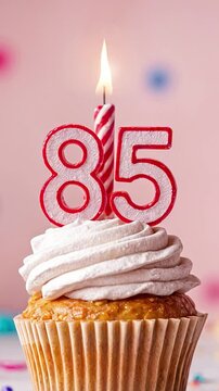 Birthday cupcake with burning lit candle with number 85. Number eighty-five for eighty-five years or eighty-fifth anniversary.