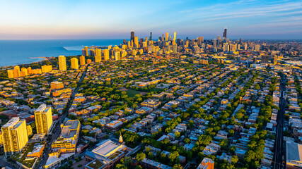 Green uptown and high-rise downtown of Chicago, Illinois in the rays of setting sun. Amazing blue waterscape of Lake Michigan at backdrop. © Vadim