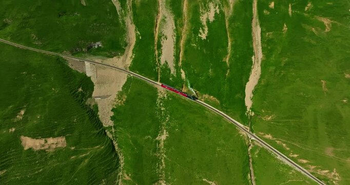 An old authentic red steam train travels of Switzerland and is a popular tourist attraction taking tourists to the top of the mountain. Cogwheel red train climbing up the mountain above lake Brienz
