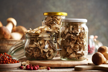 Dried and fresh wild king bolete or porcini mushrooms in glass jars